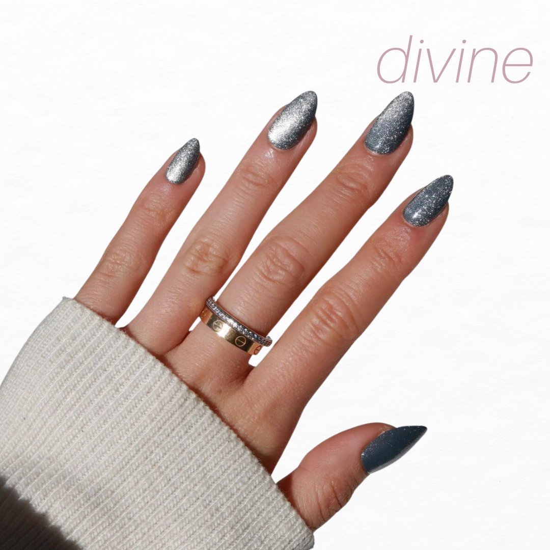 A cream sleeve partially covers a hand adorned with almond-shaped, chrome glitter nails and two gold rings. "Divine" appears in light pink on the white background, reflecting the elegance of Glowie By Her's Glam Night Out collection (20% Off).