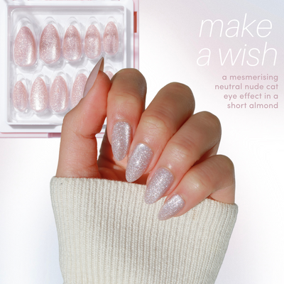 A hand showcases salon-quality, glittery almond-shaped nails on light fabric. Nearby, a similar cat eye set appears in a clear case. The text reads: "11:11 Collection Vol. 2 by Glowie By Her—make a wish with mesmerizing neutral nude cat eye effect in short almond." Now 15% off!.